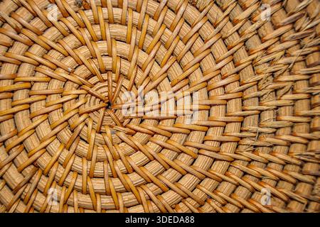 Close-up of circular woven rattan texture with a spiral pattern, showing natural brown fibers and handcrafted detail for background. Stock Photo