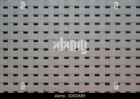 White synthetic woven material texture background with a repetitive grid pattern and small rectangular openings. Stock Photo