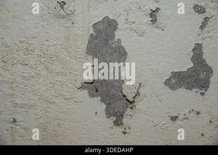 Close-up of peeling paint on a weathered concrete wall, showing aged texture and urban decay. Stock Photo