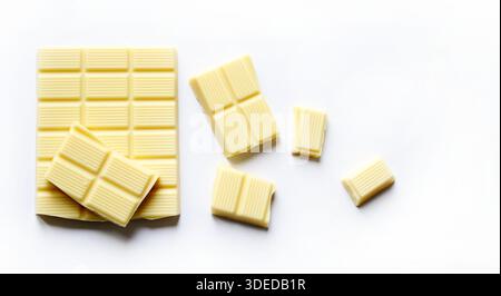 Pieces of delicious white chocolate isolated on white background. Overhead view. Copy space. Stock Photo