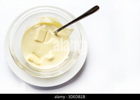 Melted white chocolate in a glass bowl isolated on a white background. Overhead view. Stock Photo