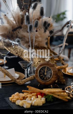 Table arrangemet with a round clock and snacks appetizers. Wooden theme - rustic style. Catering services content Stock Photo