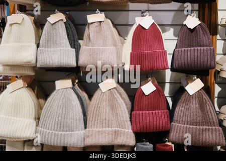 Knitted winter wool beanies hanging on display for sale in fashion store Stock Photo