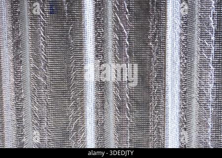 Close up texture of silver metallic insulation foil material with vertical ridges pattern showing sturdy industrial surface for temperature control pr Stock Photo