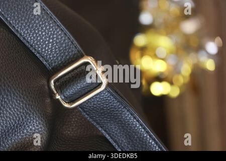 Detailed closeup view of stylish black leather strap with gold metal buckle showing luxury texture and elegance quality with festive golden bokeh ligh Stock Photo