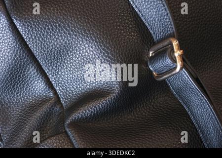 Closeup texture of elegant black leather bag with strap and metal buckle showing detailed grain pattern and sturdy craftsmanship creating luxurious an Stock Photo