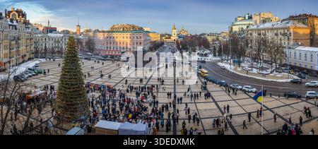 Winter view of Sofia Square in Kyiv with a New Year tree, festive crowd, snowy paving stones, and St. Michael’s Golden dome cathedral Stock Photo