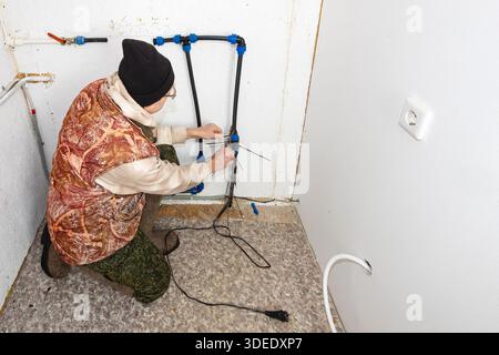 After shutting off water supply to country house for winter period homeowner installs heating cable below valve to avoid rupture in frost. Stock Photo