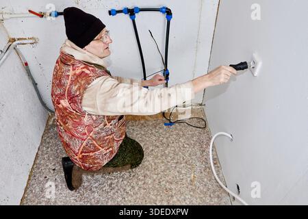 Incoming pipe to house is heated by heating cable homeowner inserts electrical plug of cable into socket in unheated utility room. Stock Photo