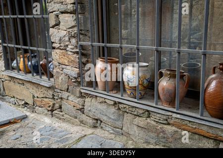 Clay pots displayed behind metal bars.. Pueblo de Patones de Arriba in Madrid, known for its slate architecture and for evading the French invasion., Stock Photo