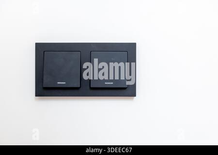 A black electrical box with four outlets. The box is on a white wall Stock Photo