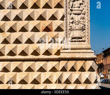 Close-up of a textured stone wall featuring pyramid-shaped patterns and ornate carvings Stock Photo