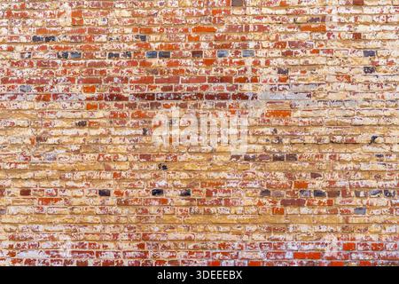 Old red brick wall. Peeling white paint on a red wall. Stock Photo