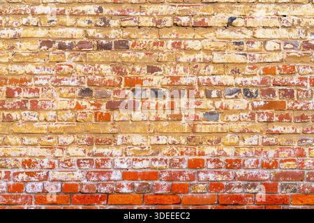 Old red brick wall. Peeling white paint on a red wall. Stock Photo