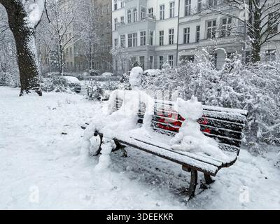 Snowman and Snowdog sitting on a bench in Berlin Kreuzberg on a snowy winter day at Grimmstrasse park. Stock Photo