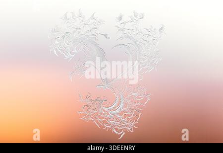 Romantic heart-shaped dragon silhouette in delicate frost ice on window glass fades to orange gradient. Stock Photo