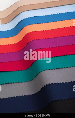 Studio close-up of colorful fabric swatches in curved folds, showing vibrant and pastel tones with pinked edges. Ideal for textile design... Stock Photo