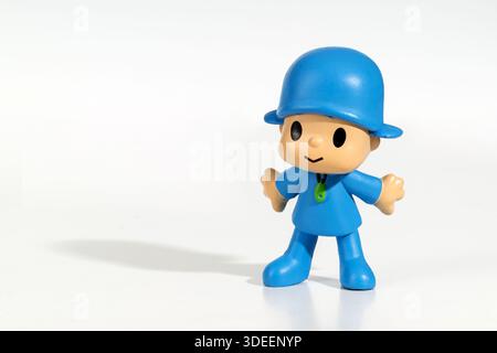 Plastic figurine of Pocoyo, a popular cartoon character, standing on a reflective white background Stock Photo