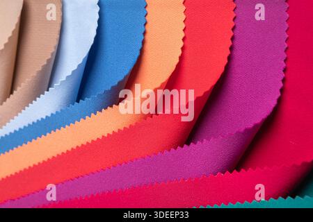 Studio close-up of colorful fabric swatches in curved folds, showing vibrant and pastel tones with pinked edges. Ideal for textile design... Stock Photo