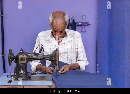 The old tailor working on the street, sewing clothes using old sewing machine. Indian tailor sewing in the street market of Mapusa Goa India-Jan 2,202 Stock Photo