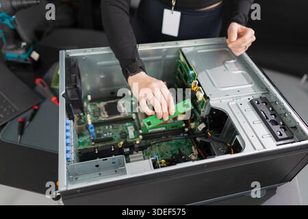 Tech worker in a server chassis upgrading RAM and components inside a desktop tower Stock Photo