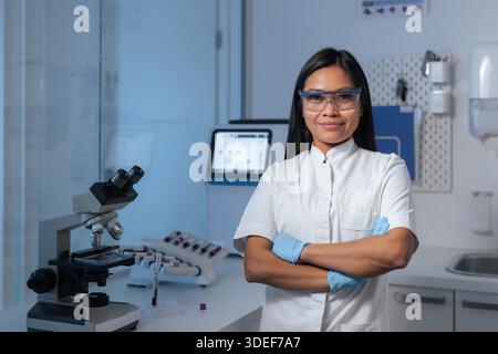 A professional Asian female scientist portrait stands confidently in a modern laboratory, engaged in research and diagnostics work. Stock Photo