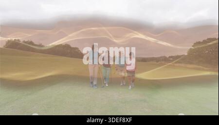 Walking four golfers holding clubs on manicured golf fairway, wearing polos and visors Stock Photo