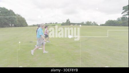 Walking four golfers carrying clubs across fairway at golf course, wearing caps, copy space Stock Photo