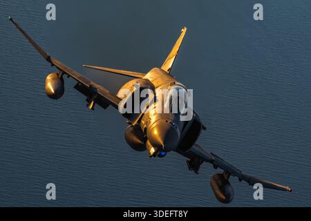 This photograph depicts a Hellenic Air Force McDonnell Douglas F-4E Phantom II in close-up air-to-air view during Athens Flying Week 2025. The twin-engine supersonic fighter, powered by two General Electric J79-GE-17A afterburning turbojet engines, shows the pilot in the cockpit, canopy, fuselage, wings, tail assembly, vertical stabilizers, and air intakes. The image emphasizes maneuverability, agility, precision, and operational performance of the aircraft. Stock Photo