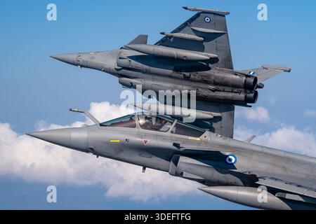 The image depicts Hellenic Air Force Dassault Rafale EG jets executing a banking formation maneuver during Athens Flying Week 2025. The twin-engine multirole fighter is powered by Snecma M88-2 turbofan engines and features delta wings, canards, bubble cockpit canopy, air-to-air refueling probe, leading-edge root extensions, and retractable landing gear. The photograph emphasizes close-up pilot view, air-to-air formation, supersonic performance, maneuverability, and operational multirole capabilities. Stock Photo