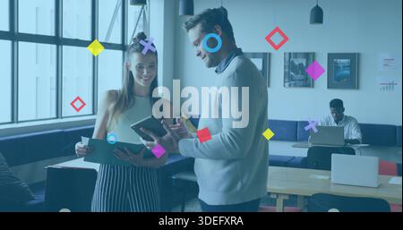 Pointing man in sweater and holding woman checking tablet and folder at coworking with graphics Stock Photo
