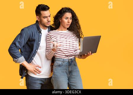 Portrait Of Confused Middle Eastern Couple Suffering Problems With Laptop Stock Photo