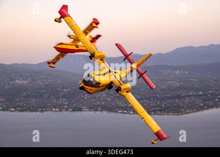 This photograph depicts Hellenic Air Force Canadair CL-215-II amphibious firefighting aircraft, registrations 2042 and 2056, serials 2042 and 2056, from the 355th Tactical Transport Squadron 'Monomakhoi tis Thymis,' banking in formation at Athens Flying Week 2025. The twin turboprop engines, low-wing configuration, cockpit, fuselage, tailplane, and water-scooping capabilities are visible, highlighting coordinated air-to-air maneuvers and precision flying. Stock Photo