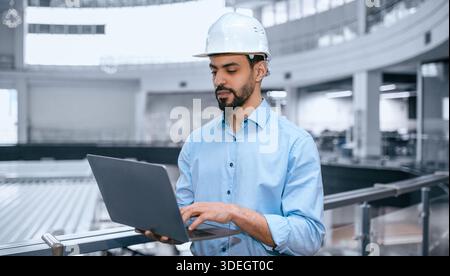Man Works on Laptop in Modern Industrial Space During Daytime Hours Stock Photo