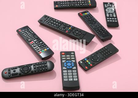 Different modern TV remote controls on pink background Stock Photo