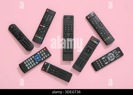 Different modern TV remote controls on pink background Stock Photo
