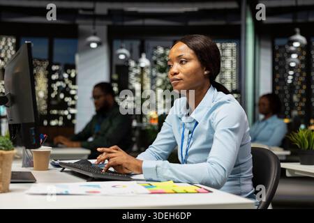 Woman office worker using data and technology for business management, reviewing statement graphs on monitor to create reports and improve efficiency, objectives achievement. Vision. Stock Photo