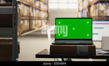 Industrial warehouse with mockup copy space on laptop at desk, import export space featuring packaging preparations for order fulfillment. Large scale e-commerce shipment process. Stock Photo