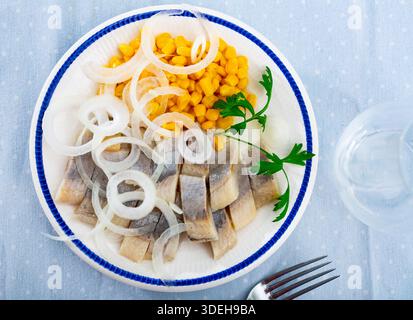 Slices of spicy marinated herring fillet with corn and onion Stock Photo
