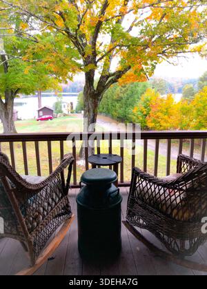 Two chairs on a porch overlooking a small lake and fall color in New England Stock Photo