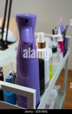 Professional manicure cosmetics and spray bottle on beauty salon trolley. Nail care products organized on workstation. Beauty industry, hygiene and Stock Photo