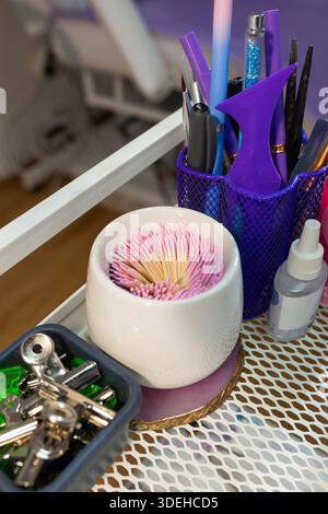 Manicure workstation details with cotton swabs, nail tools and accessories on salon trolley. Organized beauty equipment for professional nail care and Stock Photo