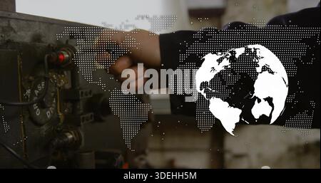 Turning tech's hand and arm at workshop, adjusting control dial in dark jacket with globe overlay Stock Photo