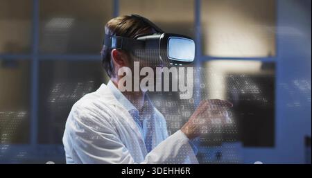 Standing man wearing VR headset and lab coat, interacting with holographic binary in tech lab Stock Photo