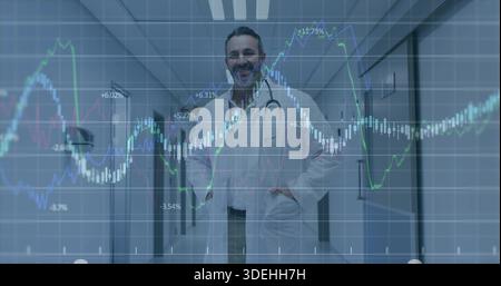 Standing male doctor wearing white lab coat and stethoscope in medical corridor, with market charts Stock Photo