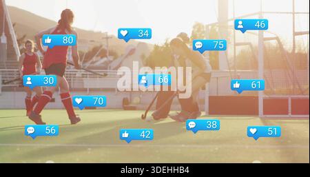 Contesting teenage hockey players in red, light uniforms vying for ball on turf, sticks, blue icons Stock Photo