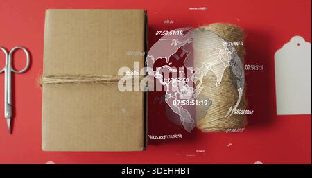 Wrapping kraft parcel with jute twine on red backdrop, showing scissors tag globe, copy space Stock Photo