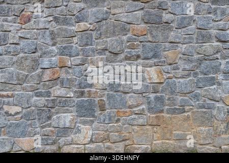 A close-up, full-frame shot of a rustic, textured natural stone wall featuring Wilmington Complex (Blue Gneiss Rocks) in Wilmington Delaware Stock Photo
