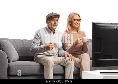 Happy mature couple on sofa watching TV and drinking coffee isolated on white background Stock Photo
