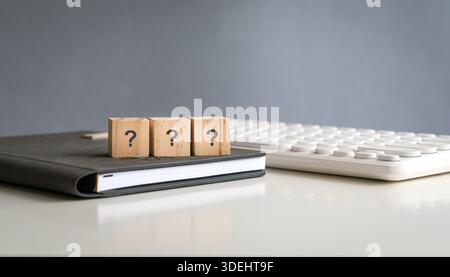 Question mark on wooden blocks, in a row, on top of book and desk. Stock Photo